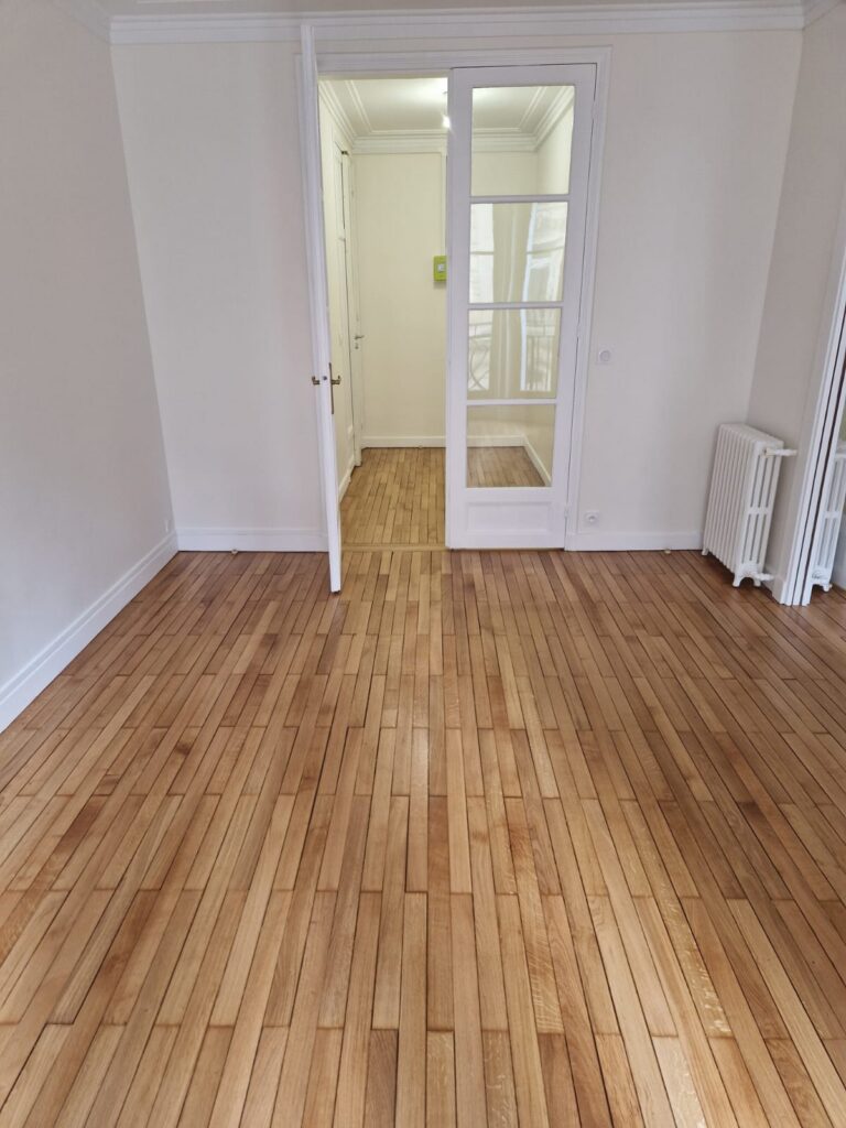 Pièce rénovée avec parquet bois Sol parquet clair, murs blancs, pièce vide, rénovation intérieure propre.