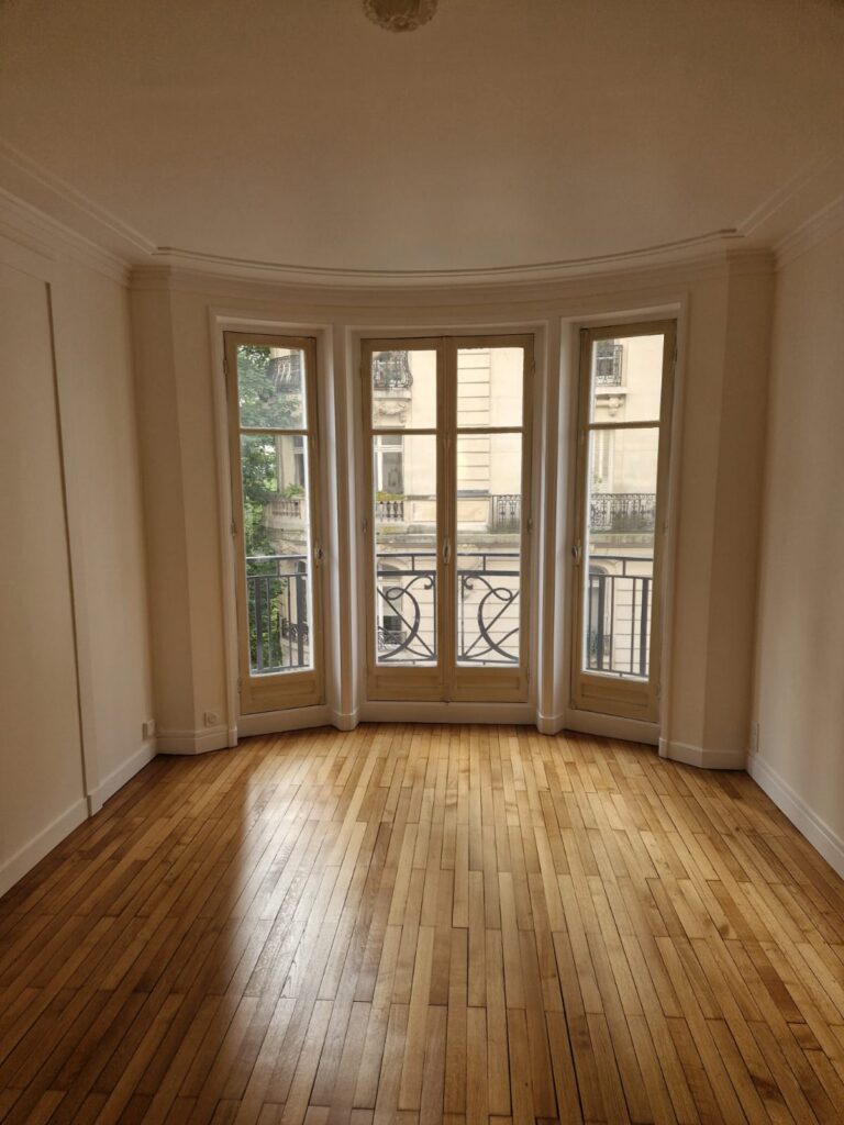 Séjour lumineux avec parquet Grande pièce, parquet bois, portes-fenêtres, lumière naturelle, rénovation intérieure.